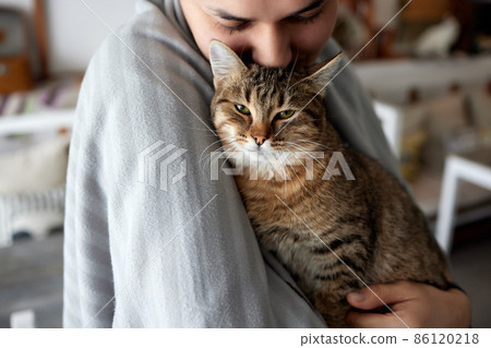 Young man in t shirt holding a cat. 86120218
