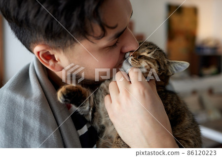 Young man in t shirt holding a cat. 86120223
