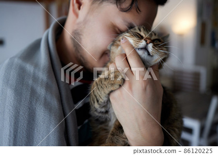Young man in t shirt holding a cat. 86120225
