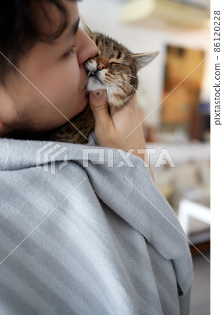 Young man in t shirt holding a cat. 86120228