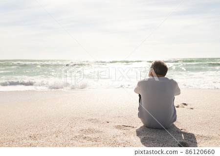 Rear view of biracial senior man looking at horizon over sea from beach shore during sunny day 86120660