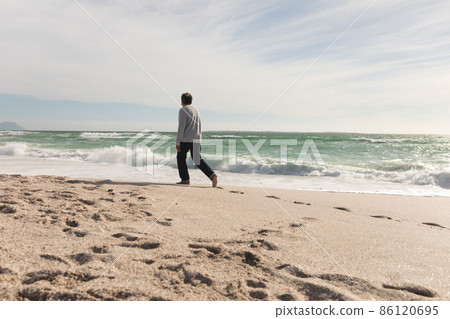 Full length of retired biracial senior man walking on shore at beach during sunny day 86120695