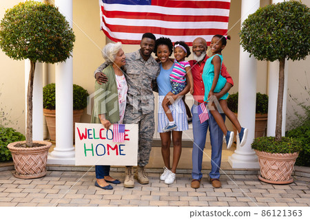 Portrait of smiling african american family standing with placard at house entrance 86121363