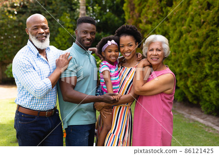 Portrait of smiling three generational african american family standing together at garden 86121425
