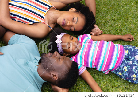 Directly above view of tired african american family sleeping together on grass at garden Directly above view of tired african american family sleeping together on grass at garden 86121434