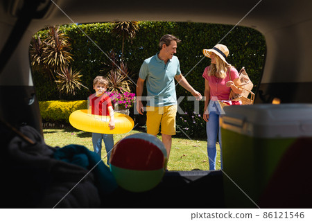 Happy caucasian family putting all their luggage in car on sunny day Happy caucasian family putting all their luggage in car on sunny day 86121546