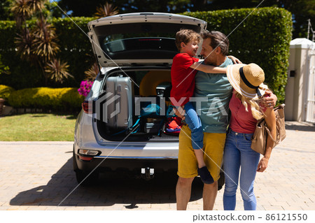 Caucasian family standing near their car smiling looking at each others Caucasian family standing near their car smiling looking at each others 86121550