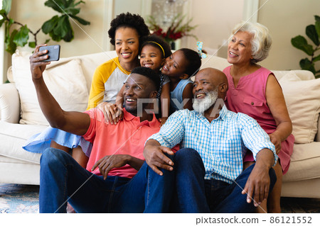Smiling african american three generation family taking a selfie sitting together on couch at home Smiling african american three generation family taking a selfie sitting together on couch at home 86121552