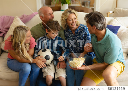 Caucasian three generation family watching tv together on the couch at home Caucasian three generation family watching tv together on the couch at home 86121639