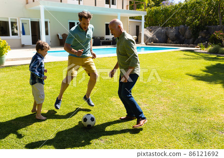 Caucasian grandfather, father and son playing football together in the garden 86121692