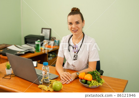 Happy female dietitian in uniform with stethoscope at workplace 86121946