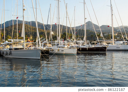Picturesque marina with sailboats and boats on background of mountains. Yalikavak Turkey. Beautiful reflection in the water of Aegean sea 86122187