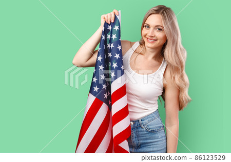 Portrait of a young woman holding USA flag isolated on color background 86123529