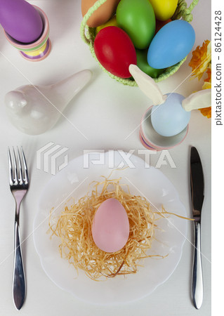 Easter table setting and dinner with  multicolored eggs. 86124428