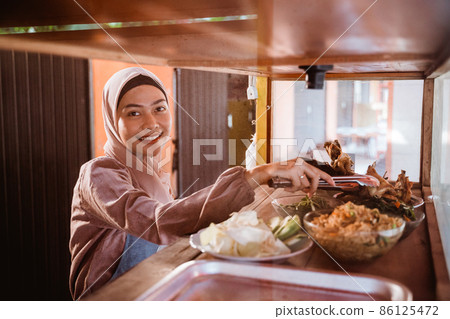 woman with hijab working in her tradtional food shop 86125472