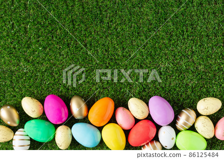 Colorful Easter eggs on grass background top view. 86125484