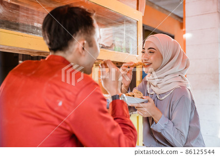 muslim couple sitting on traditional food stall, waiting for iftar time 86125544