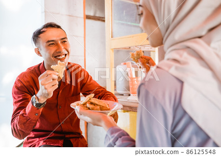 asian muslim man and woman enjoy eating some snacks 86125548