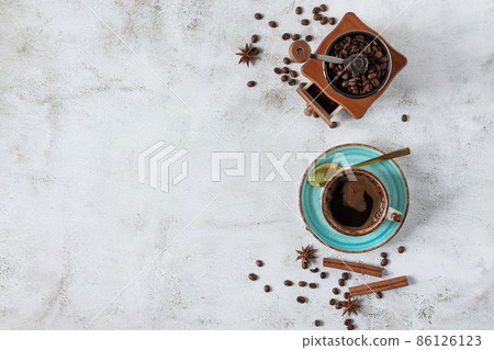 A cup of coffee with cinnamon, anise spices and vintage coffee grinder top view. A cup of coffee with cinnamon, anise spices and vintage coffee grinder top view. 86126123