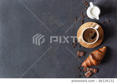 Coffee cup, milk and croissant on black background top view. Coffee cup, milk and croissant on black background top view. 86126132