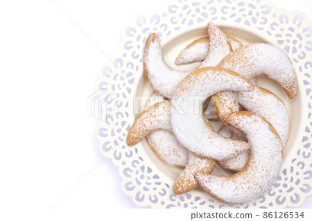 Traditional German or Austrian Vanillekipferl vanilla kipferl cookies on a plate isolated on white background Traditional German or Austrian Vanillekipferl vanilla kipferl cookies on a plate isolated on white background 86126534