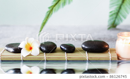 Black zen stones on grey concrete background with palm leaf near water with reflection. 86126745