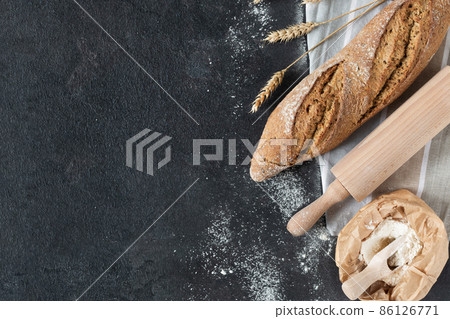 Loaf of bread with wheat ears and bag of flour on black background top view. Loaf of bread with wheat ears and bag of flour on black background top view. 86126771