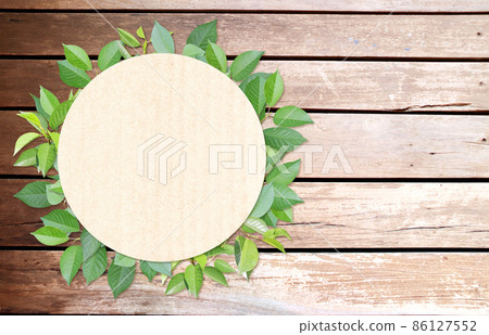 Green leaves and round paper card on wood texture. Horizontal banner with eco paper texture Green leaves and round paper card on wood texture. Horizontal banner with eco paper texture 86127552