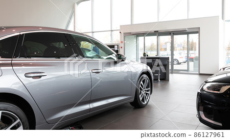 Premium car dealership entrance with gray car in the foreground 86127961