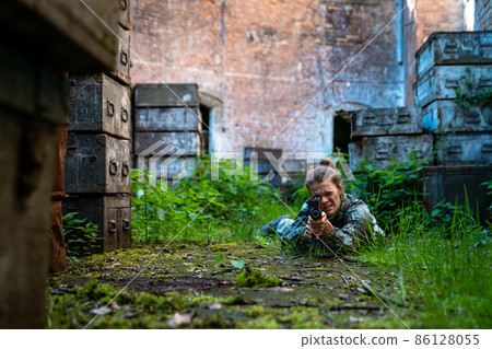 young woman in action while playing paintball young woman in action while playing paintball 86128055