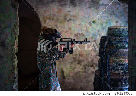 young woman in action while playing paintball 86128063