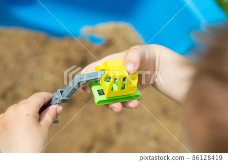 little kid is playing in sandbox with his truck toy 86128419