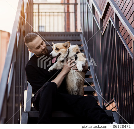 handsome man, holds welsh corgi handsome man, holds welsh corgi 86128471