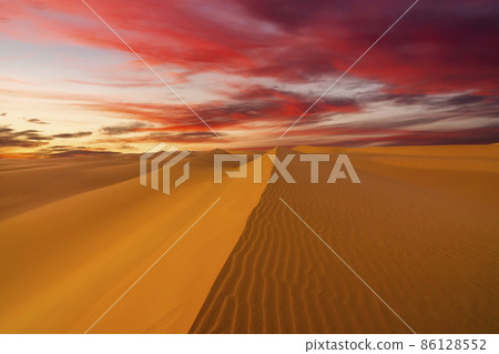 Sunset over the sand dunes in the desert. Arid landscape of the Sahara desert. Sunset over the sand dunes in the desert. Arid landscape of the Sahara desert. 86128552