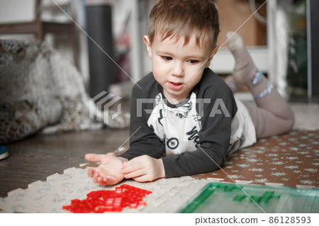 Little caucasian boy playing a board game on the floor in her room Little caucasian boy playing a board game on the floor in her room 86128593