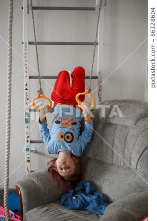 Little caucasian girl hanging on the wall bars exercising Little caucasian girl hanging on the wall bars exercising 86128604