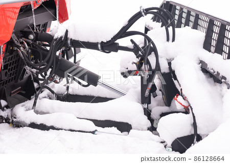 The bucket of a snowplow on tracks, standing in the forest in winter The bucket of a snowplow on tracks, standing in the forest in winter 86128664