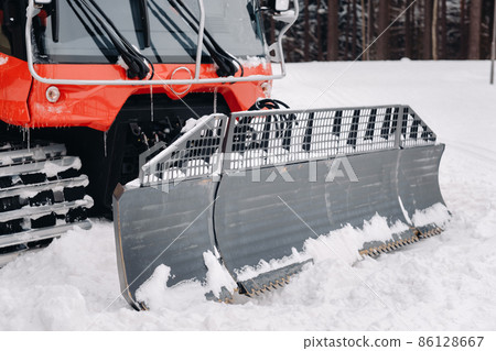 The bucket of a snowplow on tracks, standing in the forest in winter The bucket of a snowplow on tracks, standing in the forest in winter 86128667