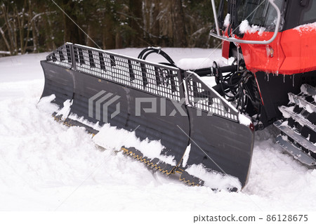The bucket of a snowplow on tracks, standing in the forest in winter The bucket of a snowplow on tracks, standing in the forest in winter 86128675