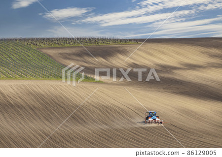 Tractor with seed drill in early spring landscape 86129005
