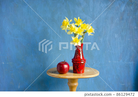 vase with narcissus and red apple 86129472