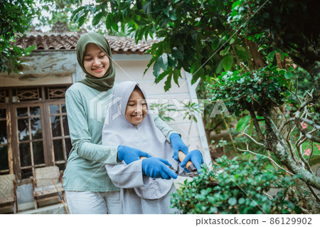 Mother helps daughter learn to use pruning shears Mother helps daughter learn to use pruning shears 86129902