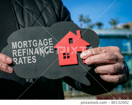 Man shows inscription Mortgage refinance rates and home. Man shows inscription Mortgage refinance rates and home. 86132002