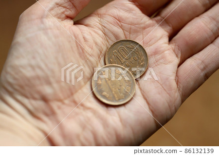手拿著舊的十日元硬幣左手拿著二十日元硬幣 86132139