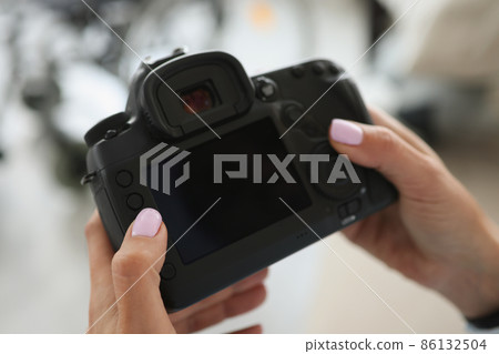 Female hands are holding a black modern camera Female hands are holding a black modern camera 86132504