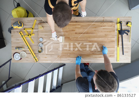 Carpenters apply varnish to a wooden surface, close-up 86133527