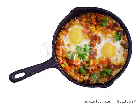 Shakshouka with eggs poached in a sauce of tomatoes and peppers isolated Shakshouka with eggs poached in a sauce of tomatoes and peppers isolated 86133587