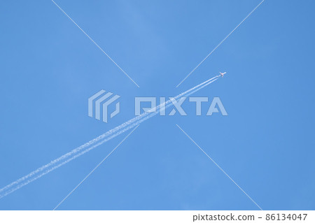 Distant passenger jet plane flying on high altitude on clear blue sky leaving white smoke trace of contrail behind. Air transportation concept 86134047