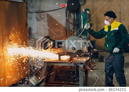 Metal processing with big angle grinder disk saw. Sparks in metalworking at factory worker 86134253