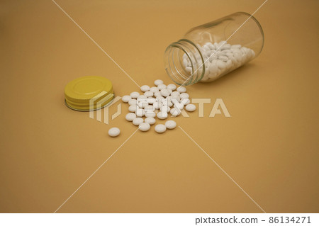 White tablets on beige paper spilled from a medicine bottle / beige background White tablets on beige paper spilled from a medicine bottle / beige background 86134271